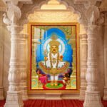 Swaminarayan Maharaj standing in colourful traditional garments beneath an ornate gold arch with a blue halo.