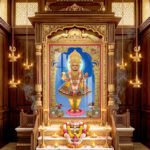 Divine figure in ornate traditional garments standing on a pink lotus pedestal, surrounded by a golden ornamental arch.