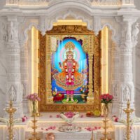 Beautiful Lord Swaminarayan murti adorned with golden jewelry, flower garlands and royal traditional dress with blue divine halo.