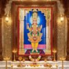 Lord Swaminarayan standing in divine pose wearing yellow traditional poshak and golden crown inside a beautifully decorated temple.