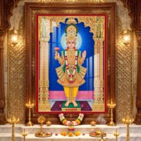 Lord Swaminarayan standing in divine pose wearing yellow traditional poshak and golden crown inside a beautifully decorated temple.